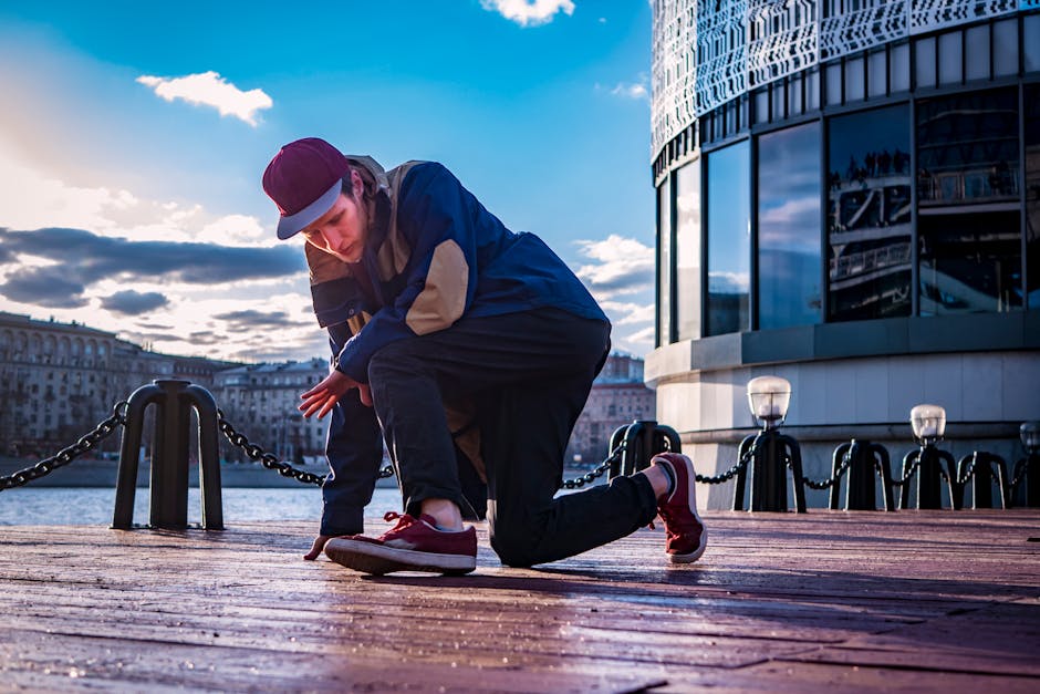 Dynamic shot of a young man breakdancing on a city pier with urban skyline backdrop.